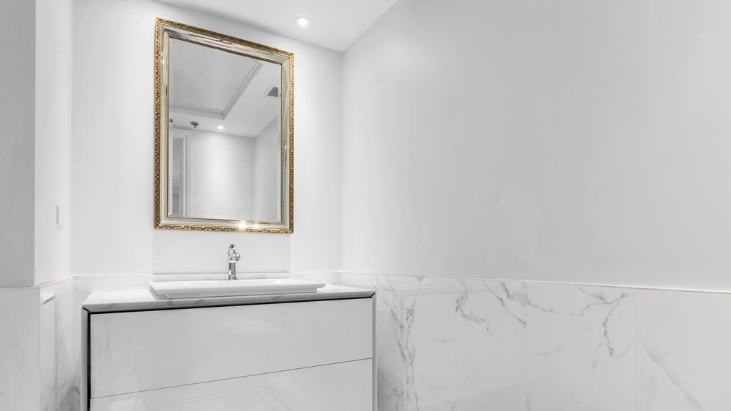 Salle d'eau du Royal Westmount iL Palazzo : vanité suspendue laquée, miroir à cadre doré et murs de pierre veinée