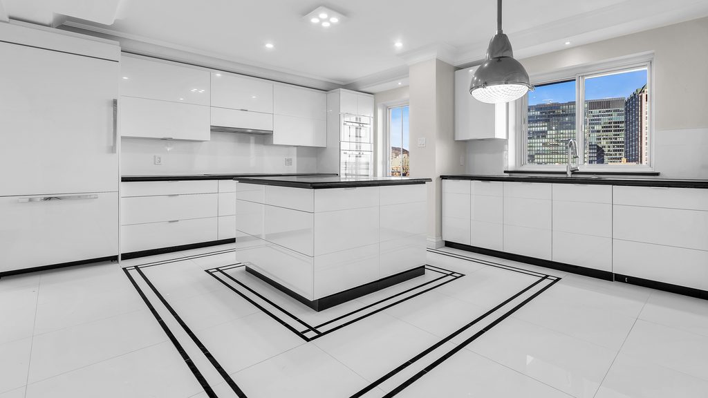 Cuisine du Royal Westmount iL Palazzo : îlot central, armoires laquées blanches et sol de pierre à incrustations noires, avec vue sur le centre-ville de Montréal